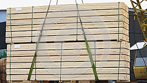 Neatly grouped timber bar is loaded into a freight train