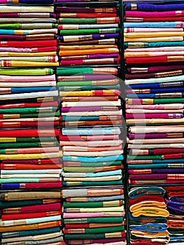 Neatly stacked colorful designer silk saris in racks in a textile shop. Incredible India