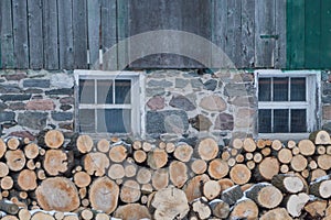 Neatly stacked firewood by an old Ontario Barn in winter