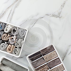 Neatly and tidy folded lingeries in organizer drawer divider on white marble background.