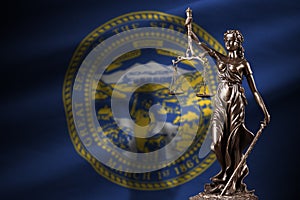 Nebraska US state flag with statue of lady justice and judicial scales in dark room. Concept of judgement and punishment