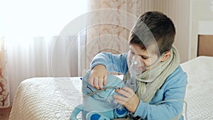 Nebulizer for inhalation, sick child breathes through nebulizer, baby does inhalation, boy with an oxygen mask on his