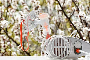 Nebulizer with a mask on the background of a blossoming tree. Spring exacerbation photo