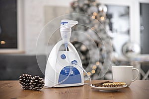 Nebulizer on the table with a cup and fir cones in the room