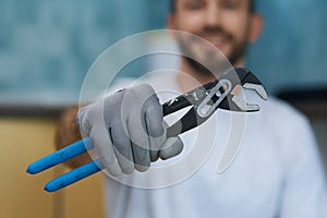 Necessary hand tool. Close up shot of hand of young repairman holding a pipe wrench