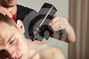 Neck gun percussion massage muscle athletic man in medical room