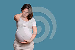 Neck pain in pregnant woman, studio shot on blue background