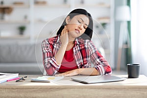 Neck Pain. Tired Asian Female Massaging Inflamed Neck After Working On Laptop