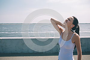 Neck pain during training. Athlete running Caucasian black hair woman runner with sport injury and touching upper back