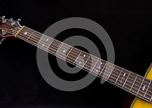 The neck of a six-string acoustic guitar on a dark background is a selective focus. guitar neck on a black background. Wooden neck