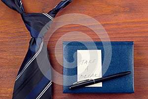 Neck tie near notepad with pen and yellow sticker