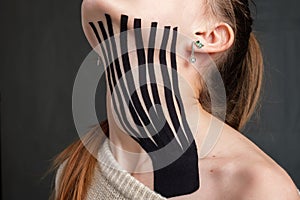 Neck of young caucasian teenager girl with placed black kinesiology tape