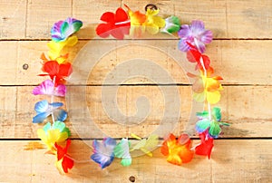 Necklace of bright colorful flowers lei on wood background