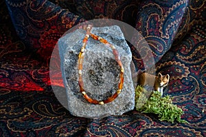 Necklace (carnelians and gold elements) presented on a stone and a decorative fox photo