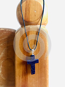 A necklace with a pendant of the holy cross hanging on a wooden stand. Vertical photo image.