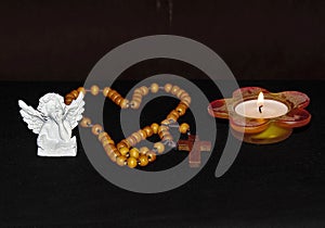 Necklace in a shape of a heart and the Christian cross along with a figure of an angel and a candle