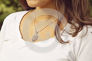 neckline wearing tiny silver chain with silver pendant in the shape of tree in mandala