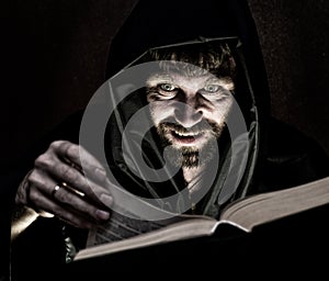 Necromancer casts spells from thick ancient book by candlelight on a dark background