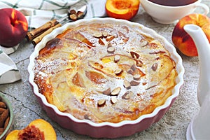 Nectarine clafoutis flan with almonds, icing sugar dressing and cup of tea