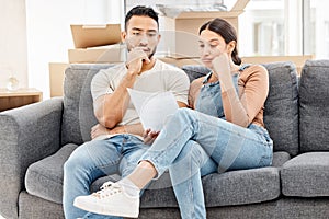 We need to make a plan about this. a young couple looking worried and reading a letter while moving house.