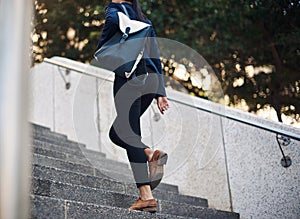 The need to succeed keeps her moving. a young businesswoman walking up stairs in the city.