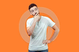 Need to think. Portrait of thoughtful brunette man holding his chin and pondering idea. indoor studio shot isolated on orange