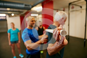 Need to work on your back. a senior man doing pvc pipe exercises with the assistance of his trainer.