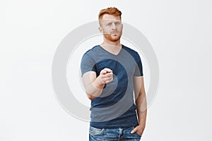 We need you, join us. Serious-looking handsome and confident mature bearded redhead male in casual blue t-shirt