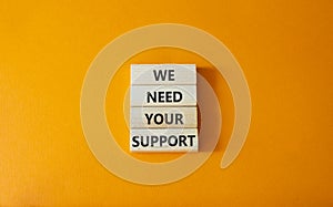 We need your support symbol. Wooden blocks with words We need your support. Beautiful orange background. Business and We need your
