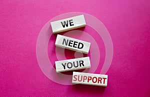 We need your support symbol. Wooden blocks with words We need your support. Beautiful red background. Business and We need your