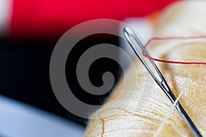 Needle eye with red thread on focus