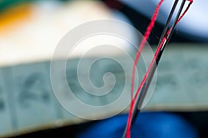 Needle eye with red thread on focus, tailor measurment tape