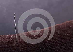 Needle in an insulated pad with black background close up