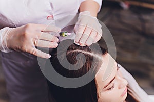 Needle mesotherapy. Cosmetic been injected in woman`s head. Thrust to strengthen hair and their growth.