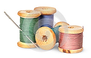 Needle and multicolored thread on wooden spool