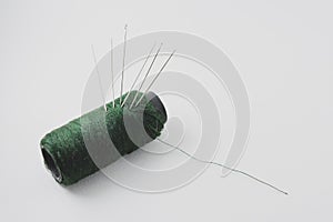 needle pierced or stick on green thread, symbol of garment industry, textile or fabric