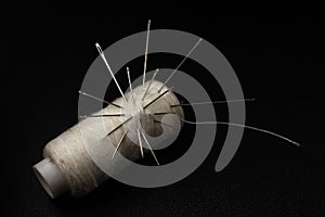 needle pierced or stick on white thread symbol of garment industry, textile or fabric with dark background