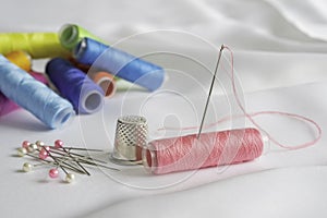 Needle, pins, thimble and colorful spools of thread