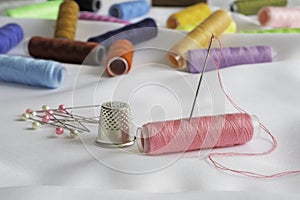 Needle, pins, thimble and colorful spools of thread