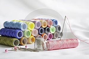 Needle, pins, thimble and colorful spools of thread