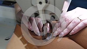 Needle of sewing machine in motion. a seamstress sews black leather in a sewing workshop. needles of sewing machine