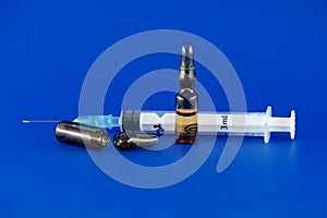 Close-up view of syringe and ampoule over blue