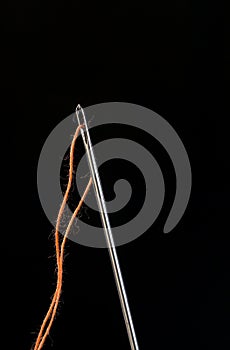 Needle and thread through on black background