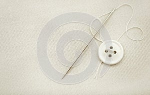 The needle and thread lie on a white cloth. Button on clothes. Seamstress and tailor tools