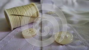 Needle on thread reel and white button