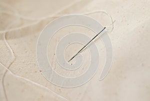Needle with thread. Spool of thread. Sewing. Sewing machine. Seamstress. Sewing. White threads. Handmade. The cloth