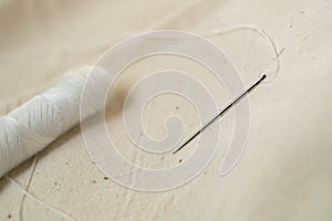 Needle with thread. Spool of thread. Sewing. Sewing machine. Seamstress. Sewing. White threads. Handmade. The cloth