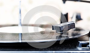 The needle of a turntable playing the tracks of a black vinyl record