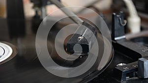 The needle of a turntable playing the tracks of a black vinyl record