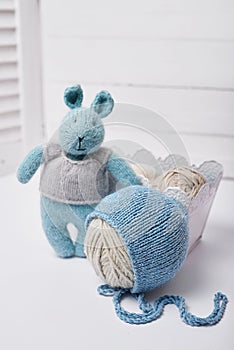Needlework and knitting. Hobbies and creativity. Knit for children. Knitted toys rabbit and hat. Handmade toy hare. Baby cap. Yarn